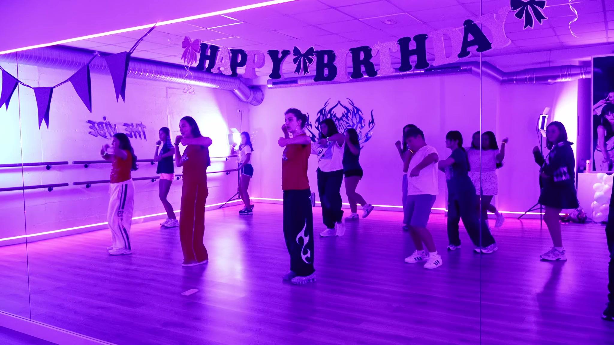 Niñas y niños bailando bajo la guirnalda de «Happy Birthday»