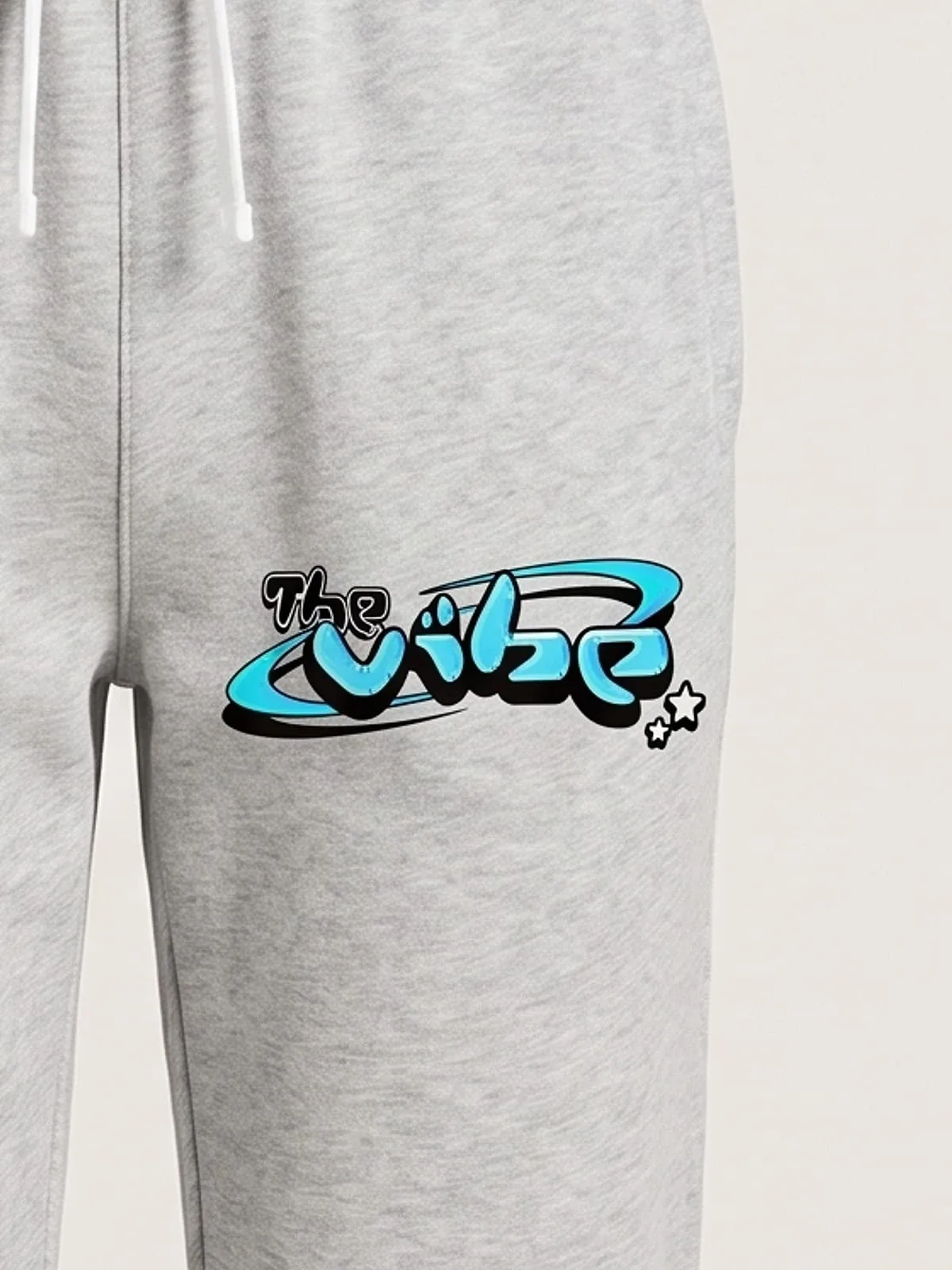 Detalle del logo de The Vibe en cian estampado en el pantalón jogger gris