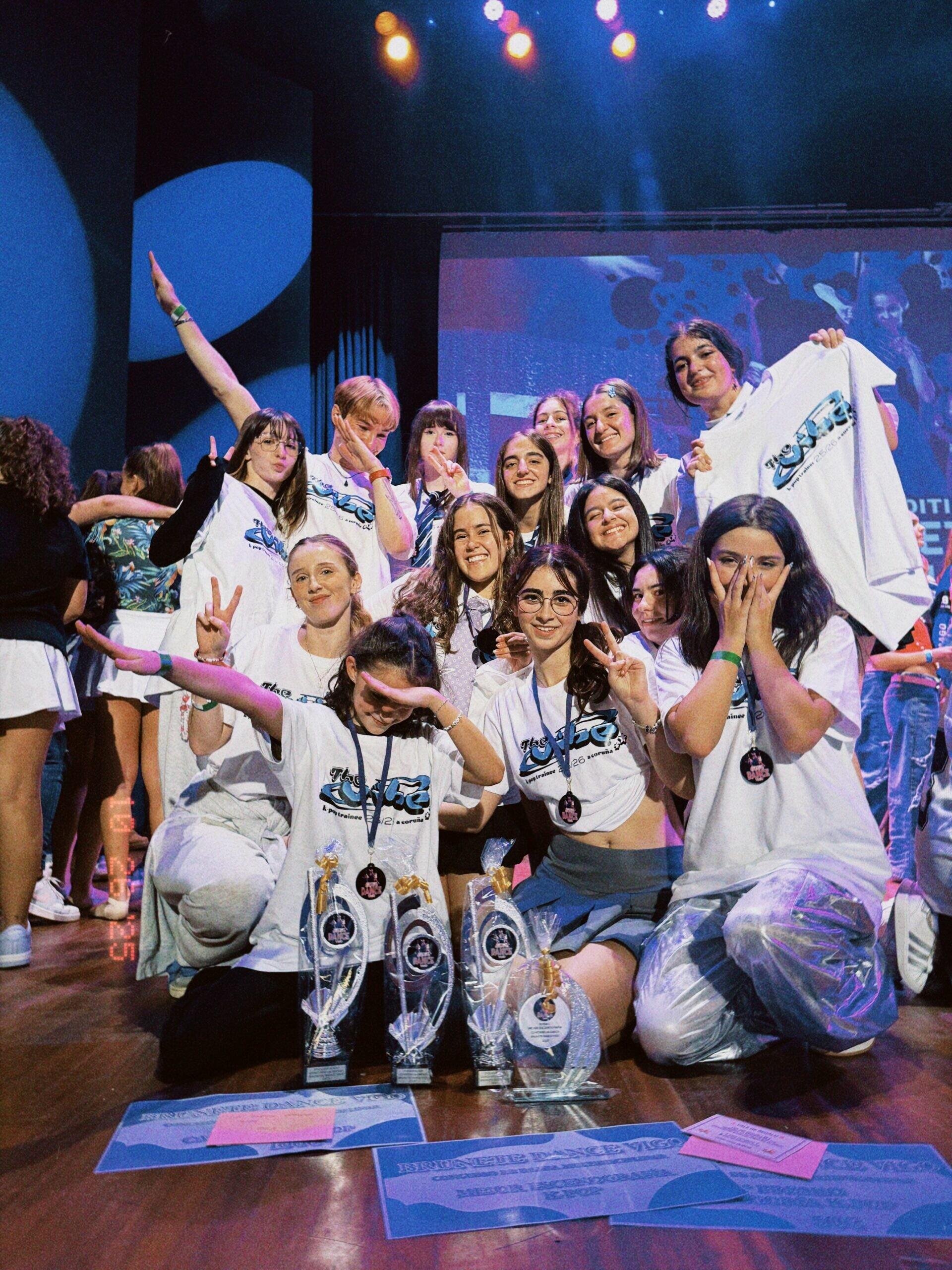El equipo de K-pop de The Vibe Studio celebrando sobre el escenario con sus trofeos