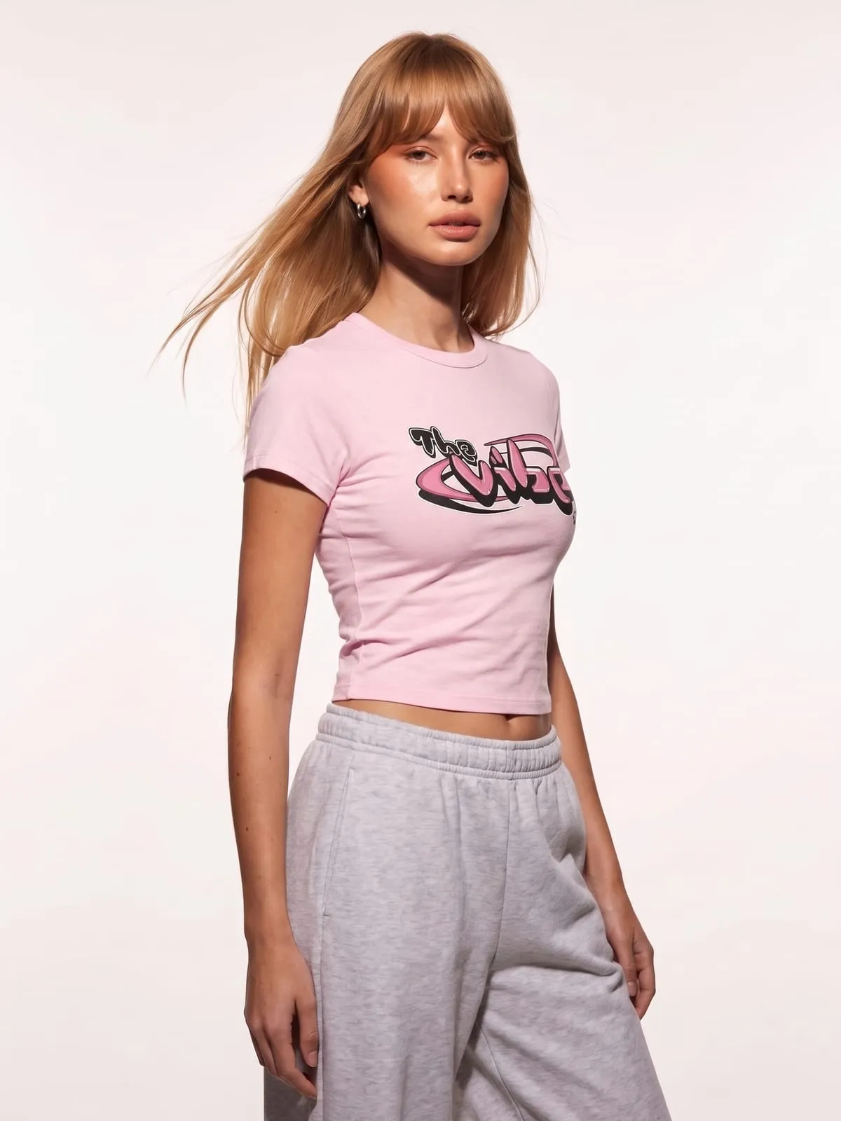 Modelo con la baby tee rosa de The Vibe, de tres cuartos