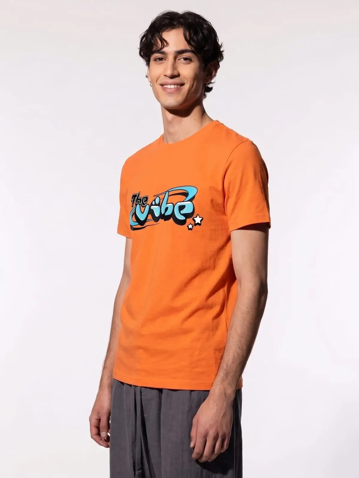 Chico con la camiseta naranja de The Vibe, de tres cuartos