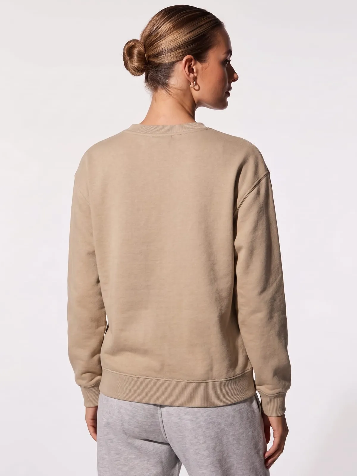 Modelo con la sudadera arena de The Vibe, de espaldas