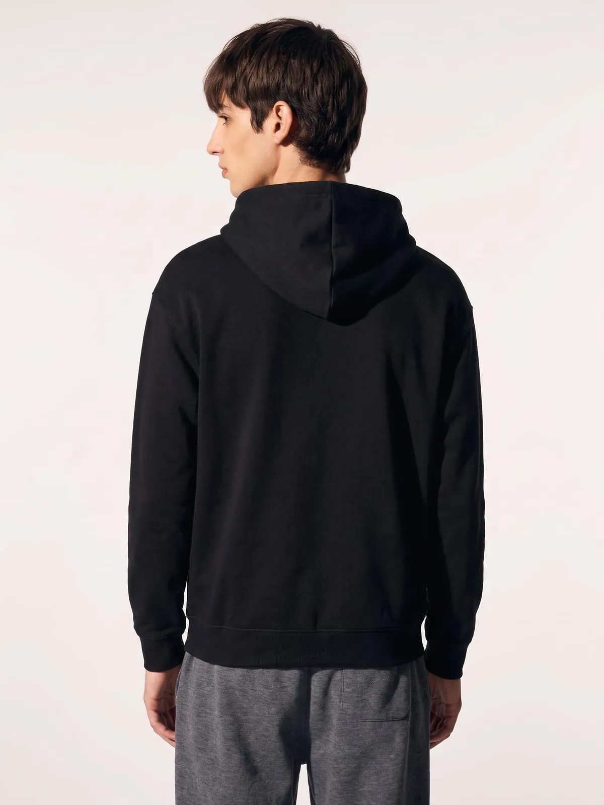 Modelo con la sudadera con capucha negra de The Vibe, de espaldas